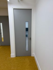 A paint grade door with a vision panel and aluminium trim